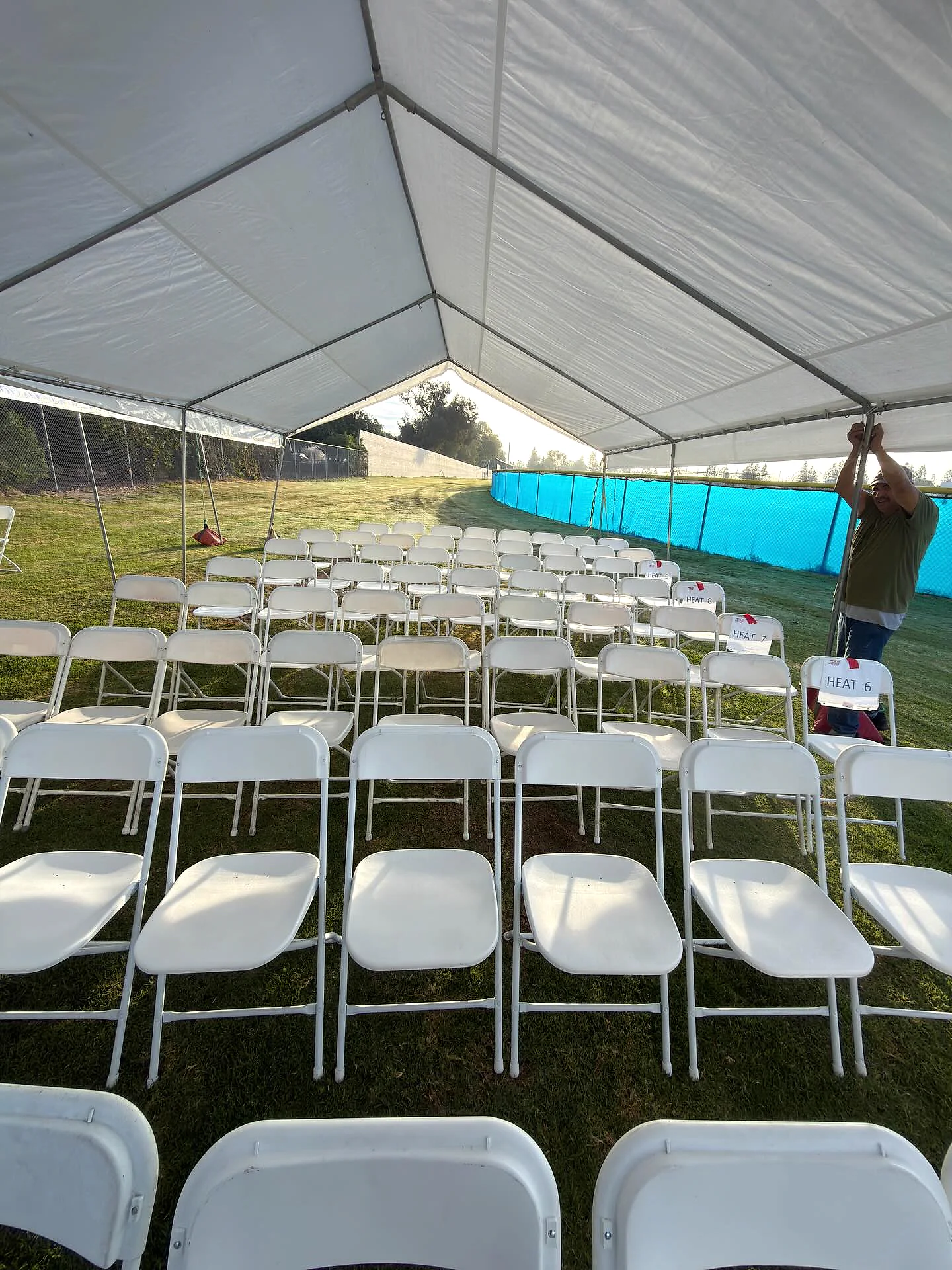 Rows of white ceremony chairs aligned under an outdoor canopy