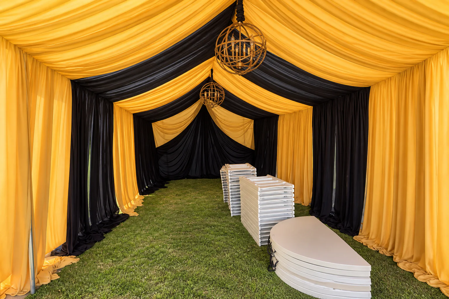 Gold-and-black fabric draping and chandeliers installed inside an event canopy