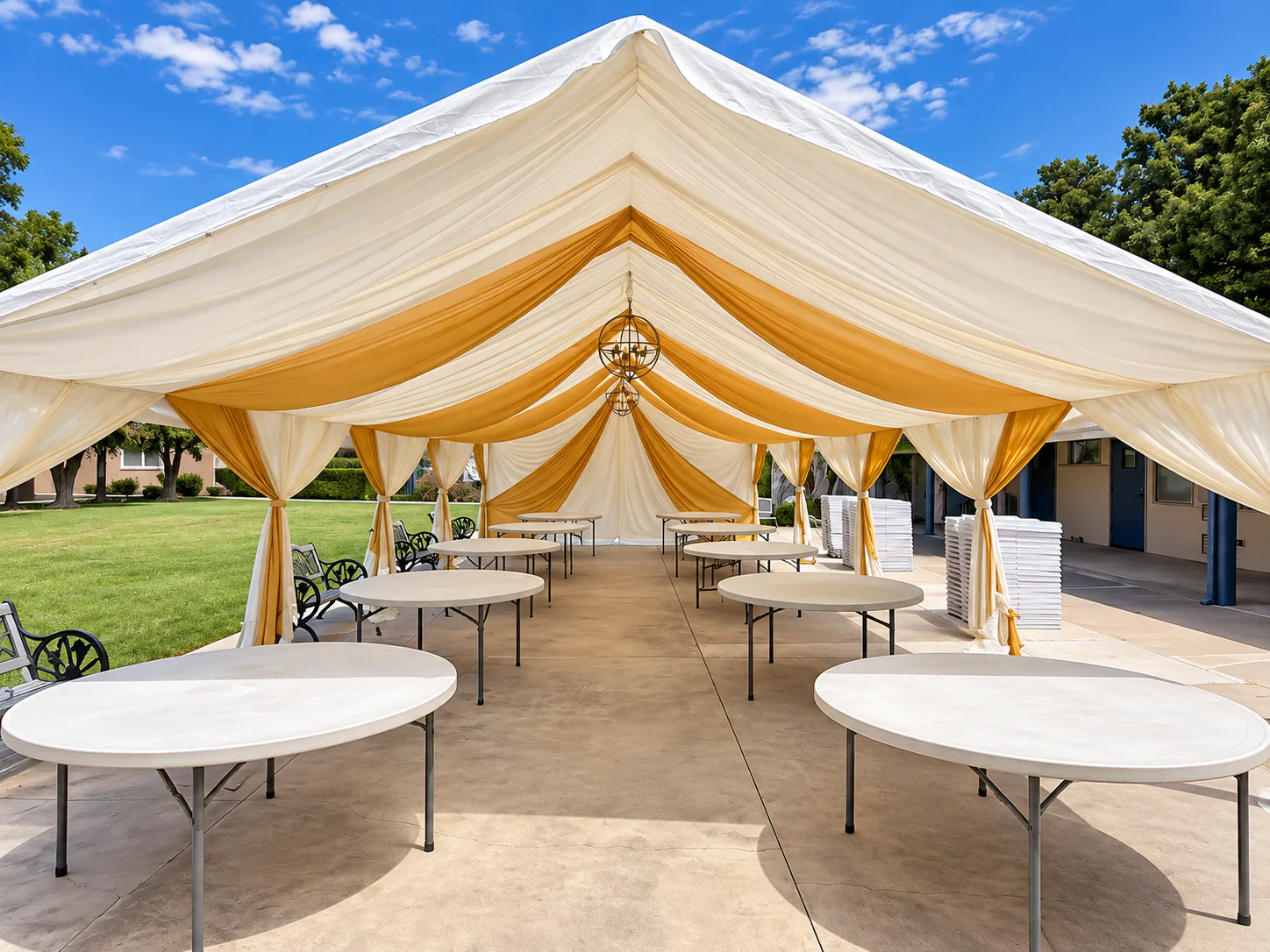 Gold-and-white ceiling draping and chandeliers installed inside a large canopy