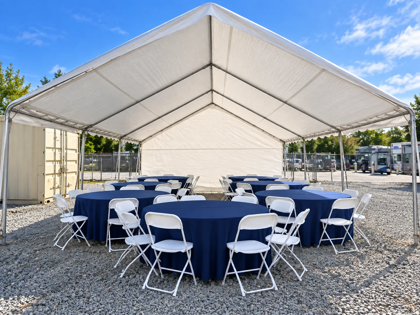 Round tables with navy linens and white folding chairs inside a canopy